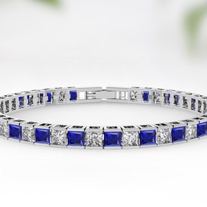 May include: A silver tennis bracelet with alternating blue sapphire and clear cubic zirconia stones.