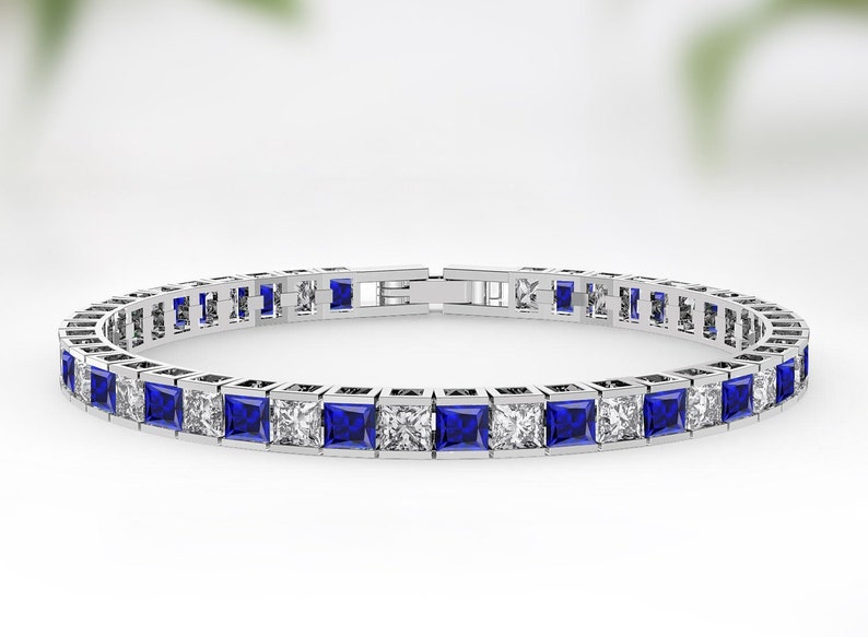 May include: A silver tennis bracelet with alternating blue sapphire and clear cubic zirconia stones.