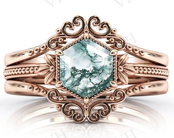 May include: A rose gold ring with a hexagonal green and white agate gemstone set in a delicate filigree design. The ring is surrounded by three bands of rose gold with beaded details.