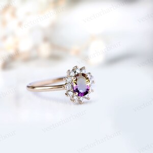 Puede incluir: Un anillo de oro con una piedra ovalada de color p&uacute;rpura y amarillo rodeada por un halo de diamantes m&aacute;s peque&ntilde;os.