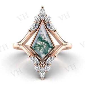 Puede incluir: Un anillo de oro rosa con una piedra preciosa de ágata musgosa verde y blanca engastada en un marco de forma de diamante. El anillo está adornado con un grupo de pequeños diamantes transparentes a cada lado de la piedra preciosa.