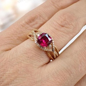 May include: A gold ring with a large, square-cut, pink gemstone surrounded by smaller diamonds. The ring has a delicate, twisted band.