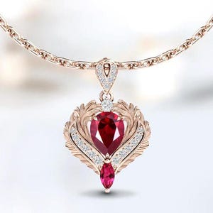 May include: A rose gold pendant necklace featuring a large, pear-shaped, deep red gemstone at the center, surrounded by a decorative, openwork design. The pendant is accented with small, clear gemstones and hangs from a delicate chain.