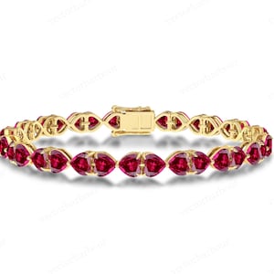 May include: A gold bracelet with a heart-shaped ruby gemstone design. The bracelet is made of yellow gold and features a clasp closure.