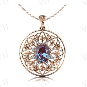 Puede incluir: Un collar con un colgante de oro rosa con una gran piedra de alexandrita ovalada rodeada de diamantes más pequeños en un delicado diseño floral.