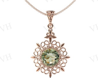 Può includere: Una delicata collana d'oro con un ciondolo rotondo di pietra verde incastonato in un design a filigrana.