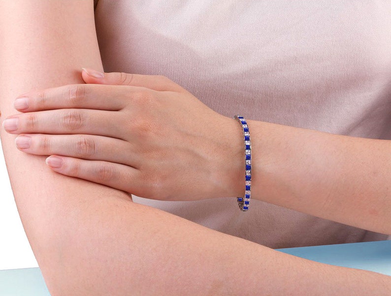 May include: A silver bracelet with alternating blue and white square-shaped stones.