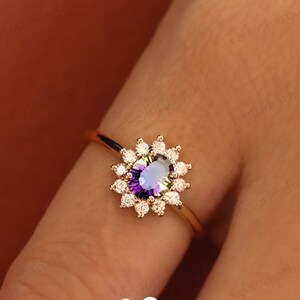 Puede incluir: Un anillo de oro con una piedra preciosa p&uacute;rpura y verde rodeada por un halo de peque&ntilde;os diamantes.