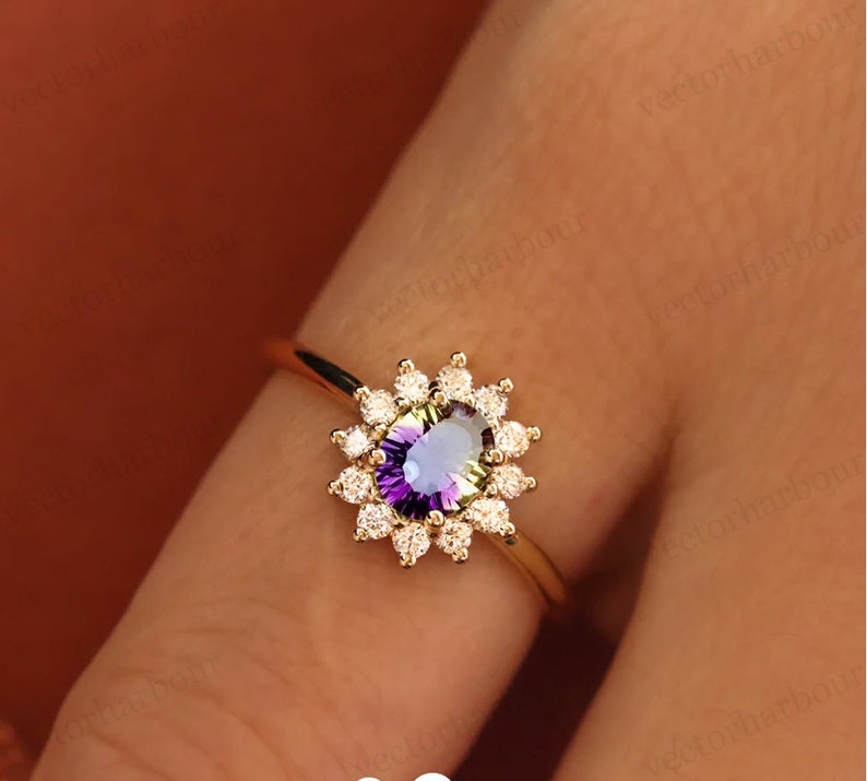 Puede incluir: Un anillo de oro con una piedra preciosa p&uacute;rpura y verde rodeada por un halo de peque&ntilde;os diamantes.