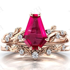 May include: A rose gold engagement ring set with a large, deep red, octagon-shaped gemstone and smaller, round, white gemstones set in a delicate, leafy design.