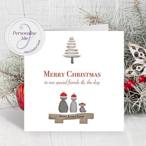 May include: A square white greeting card featuring a stylized gray pebble Christmas tree, the red text Merry Christmas to our special friends & the dog, and three gray pebble figures wearing red Santa hats on a wooden bench labeled David, Kath & Patch.