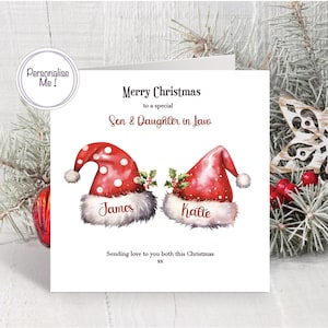 May include: A square greeting card featuring two red Santa hats with white polka dots and fur trim, decorated with holly. The text reads Merry Christmas to a special Son & Daughter in Law, James, Katte, and Sending love to you both this Christmas xx.