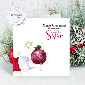 Erstaunliche Schwester personalisierte, atemberaubende Weihnachtskarte mit dem roten Handschuh des Weihnachtsmannes, der eine schöne Kugel präsentiert, die mit dem Namen der Schwester personalisiert ist