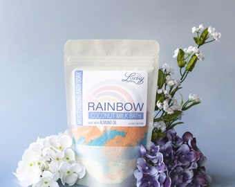 May include: A white pouch with a rainbow design and the text "Rainbow Coconut Milk Bath" and "Luxiny" on the front. The pouch contains a colorful bath soak.