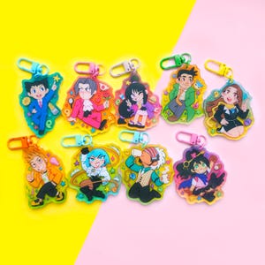 May include: Set of ten colorful cartoon character keychains. Each keychain features a different character with a unique design and bright colors. The keychains are made of clear acrylic and have a metal ring for attaching to keys or bags.