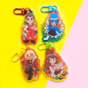 May include: Four colorful keychains featuring anime characters. Each keychain has a different character with a unique design and background. The keychains are made of clear acrylic and have a metal ring for attaching to keys.