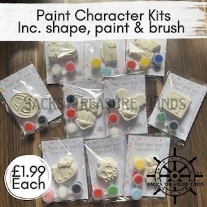 May include: A collection of paint character kits, each containing a white plaster shape, a small paintbrush, and several small pots of coloured paint, all individually packaged in clear plastic bags with printed instruction cards.