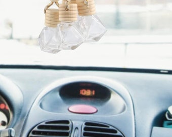 May include: Four diamond-shaped glass car air fresheners with wooden caps hanging from a rearview mirror in a car. The fresheners are hanging from strings with wooden beads.