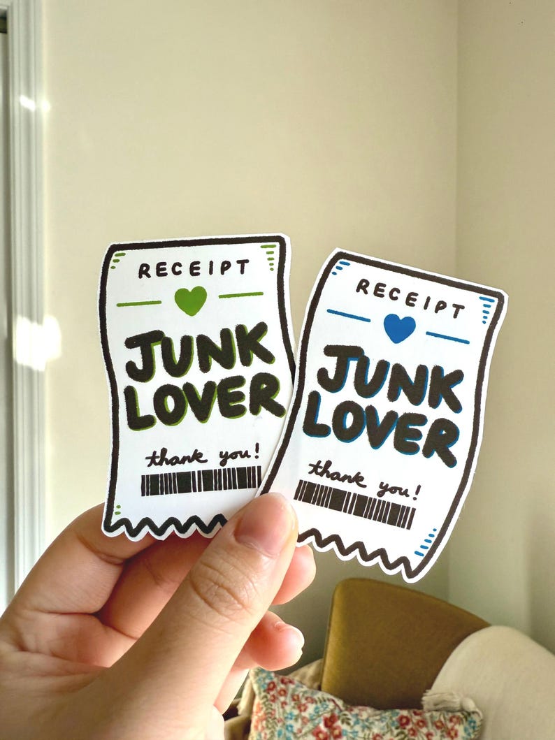 May include: Two white stickers in the shape of receipts, held by a hand. The stickers have the word "RECEIPT" at the top, a heart, and the words "JUNK LOVER" in bold letters. Below is a barcode and the words "thank you!"