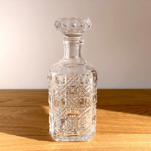 Beautiful mid century cut clear glass decanter. Rectangular in shape with a plaid cut pattern on all sides and a diamond cut pattern solid glass stopper.