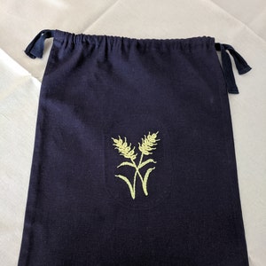 May include: A dark blue drawstring bag with a yellow embroidered wheat design.