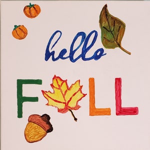 Puede incluir: Una tarjeta de felicitación pintada a mano con las palabras "hello fall" en azul, verde, naranja y rojo. La tarjeta presenta una hoja de arce amarilla, una bellota marrón y una hoja marrón.