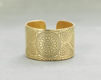 Könnte beinhalten: Ein goldfarbener Metallring mit einem komplizierten, gravierten Design. Das Design zeigt ein kreisförmiges Muster mit paisleyartigen Motiven.
