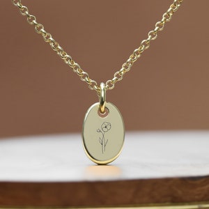 May include: A gold chain necklace with a small oval pendant featuring an engraved flower design.