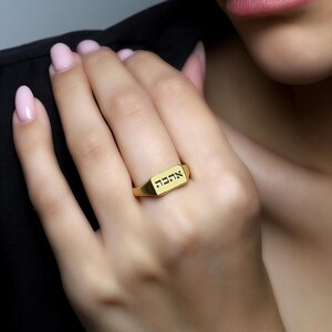 Puede incluir: Un anillo de sello de oro con la palabra hebrea "אהבה" (amor) grabada en la parte superior.