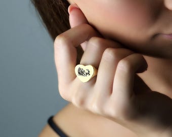 May include: A gold heart-shaped ring with a black and white image of Santa Claus in a sleigh pulled by reindeer.