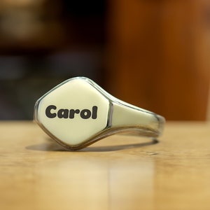 May include: A silver signet ring with the name "Carol" engraved on the top.
