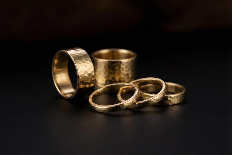 A collection of gold-colored rings with a textured, embossed appearance, arranged on a dark background.