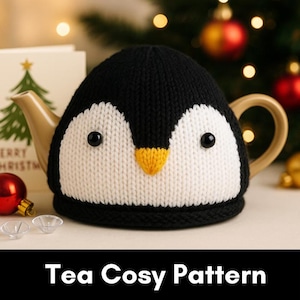 Puede incluir: Un calentador de té tejido en forma de pingüino, con colores negro, blanco y amarillo. El pingüino tiene ojos negros y un pico amarillo. El calentador de té está sobre una tetera beige con un asa dorada. El texto "Tea Cosy Pattern" está en la parte inferior de la imagen.