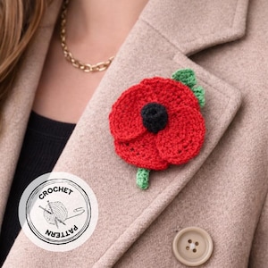 May include: A handmade crochet poppy pin with red petals and a black center, accented with green leaves and stem. The pin is attached to a beige coat. A round logo with the words "CROCHET PATTERN" is visible.