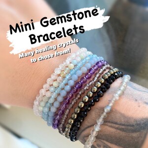 May include: A stack of colorful gemstone bracelets on a person's wrist. The bracelets are made of various healing crystals, including amethyst, aquamarine, and moonstone.  Mini Gemstone Bracelets. Many healing crystals to chose from!