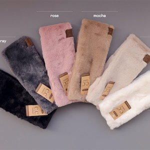 May include: Six faux fur neck warmers in various colors, including black, dark gray, rose, mocha, beige, and ivory. Each warmer has a brown leather tag with the letters "C.C" printed on it.
