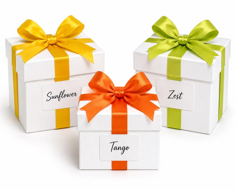 May include: Three white gift boxes with colorful bows and ribbons. The boxes are labeled "Sunflower", "Tango", and "Zest". The bows are yellow, orange, and green. The ribbons match the bow colors.