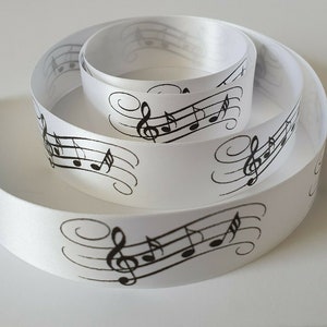 May include: White satin ribbon with a black musical note design. The ribbon is rolled up and shows the design on both sides.