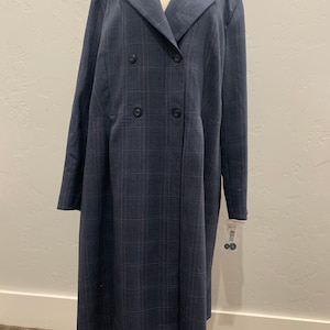 May include: A long, navy blue plaid dress with a double-breasted closure and a v-neckline. The dress has a fitted bodice and a flowing skirt.