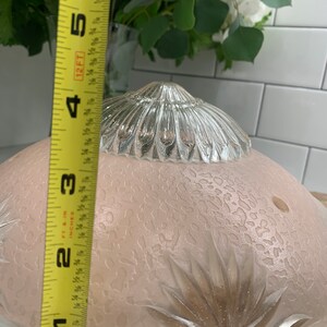 May include: A clear glass ceiling light fixture with a frosted, textured glass shade and a silver metal top. The shade has a floral design and a diameter of approximately 7 inches.