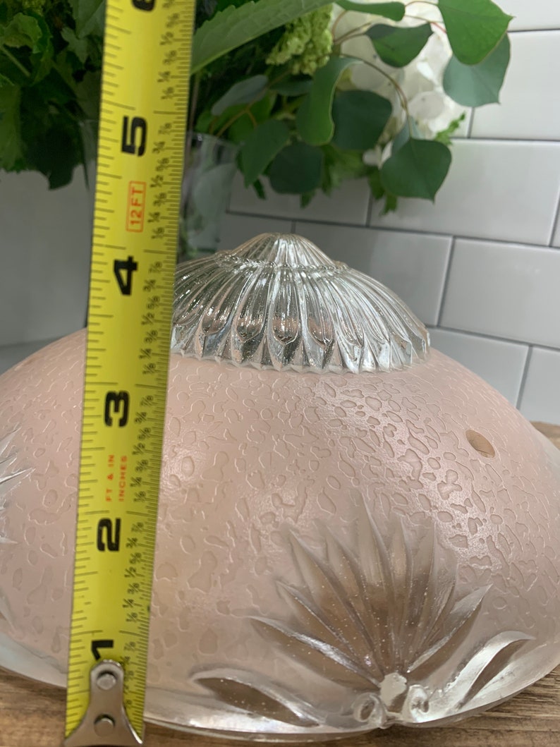 May include: A clear glass ceiling light fixture with a frosted, textured glass shade and a silver metal top. The shade has a floral design and a diameter of approximately 7 inches.
