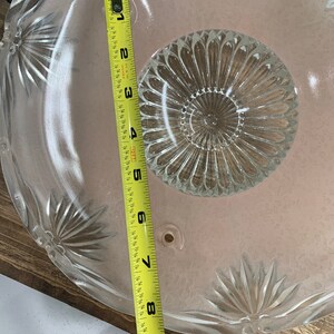 May include: A clear glass ceiling light fixture with a scalloped edge and a central, circular, textured design. The fixture measures 9 inches in diameter.