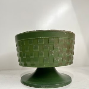 May include: A green ceramic planter with a woven pattern and a pedestal base.