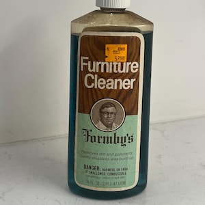 Puede incluir: Una botella de plástico transparente llena de limpiador de muebles líquido azul. La etiqueta presenta el texto Furniture Cleaner, Formby's y un retrato de una persona. Incluye una etiqueta de precio amarilla e indica .47 LITRE.
