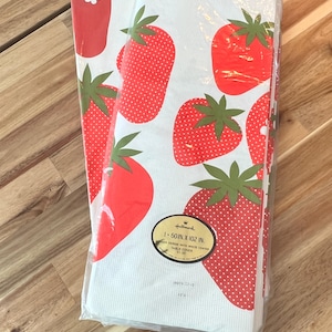 May include: A Hallmark table cover featuring a white background and a pattern of large red strawberries. The strawberries have green leaves and white seeds. The table cover measures 152 cm by 259 cm.