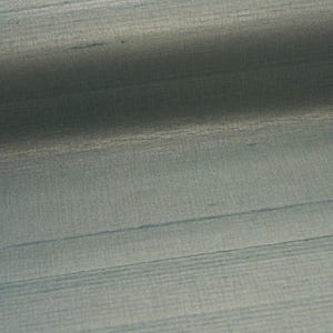 May include: A close-up of a textured, light blue fabric with horizontal lines and subtle variations in tone. The fabric has a slight sheen, and the lines create a sense of depth and dimension. The overall effect is one of understated elegance.