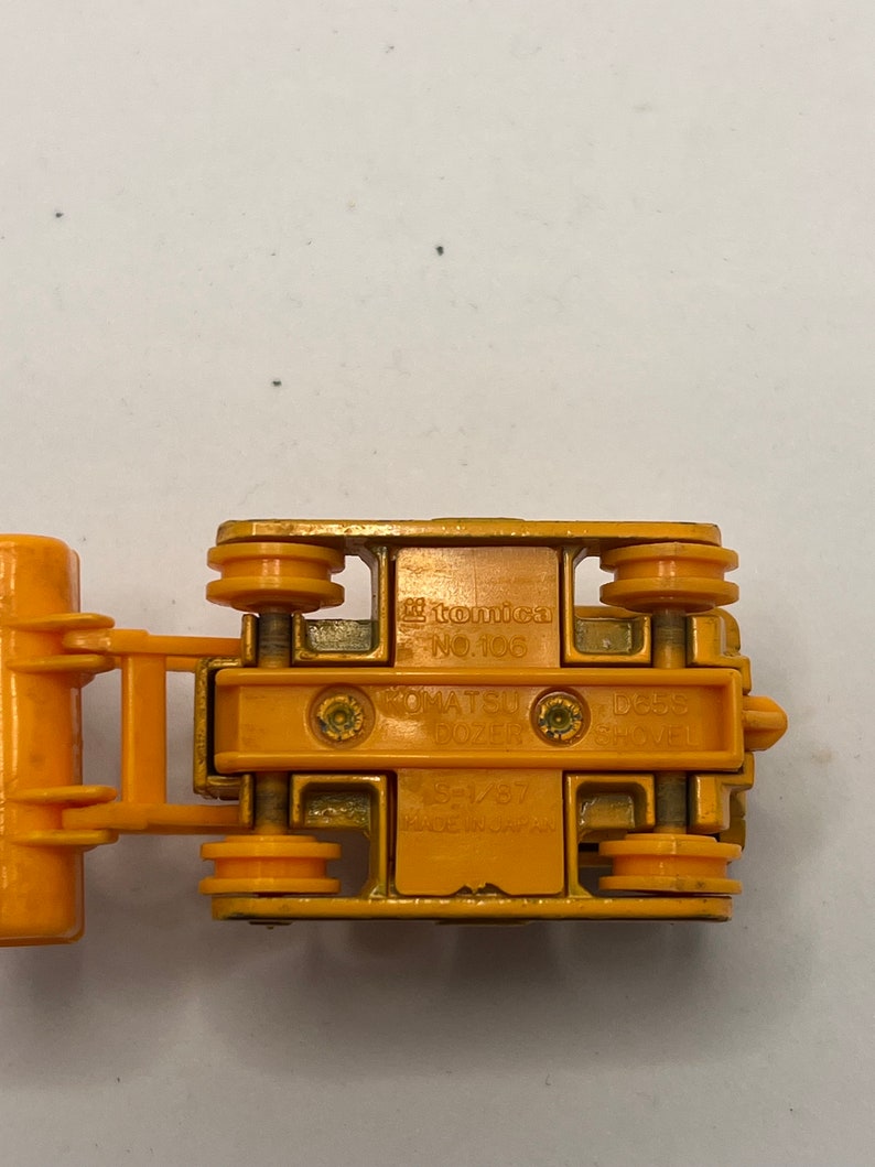 Pu&ograve; includere: Un veicolo da costruzione giocattolo giallo, un Komatsu D65S Shovel Dozer, della serie Tomica No. 106. Il giocattolo &egrave; fatto in Giappone ed &egrave; un modello in scala 1/87.