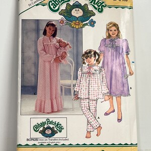 May include: A vintage sewing pattern for Cabbage Patch Kids clothing. The pattern includes three different outfits: a pink nightgown, a purple nightgown, and a plaid pajama set. The pattern is for sizes 7-8-10 and includes iron-on transfers.