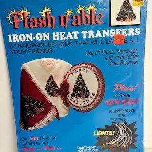 May include: Package of Flash 'n' Able Iron-On Heat Transfers for crafting. The package features a red and white Christmas design with a festive tree and the words "Merry Christmas". The package also includes a set of lights and the text "Plus! A Great New Idea! Designed to use with or without lights!"