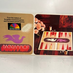 Puede incluir: Una caja de juego de backgammon vintage con un logotipo de pájaro morado y el texto "BACKGAMMON". La caja presenta una rueda colorida con el texto "Selchow & Righter" y una foto de un tablero de backgammon listo para jugar.